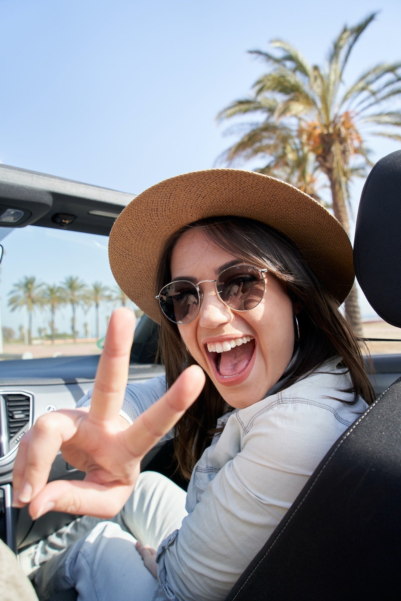 Vertical portrait pretty young hipster big smile in convertible car. People renting car vacation.